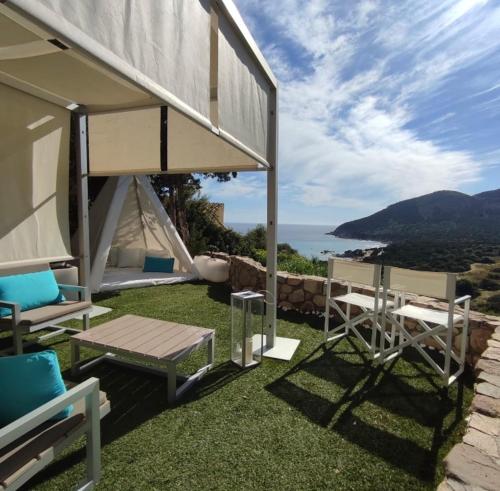 a patio with chairs and a table and a tent at Villa Sardinia Seaview&SPApool in Villasimius