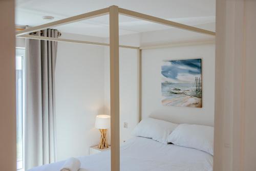 a white bedroom with a canopy bed and a window at Sennen Cove Cottage in Sennen Cove