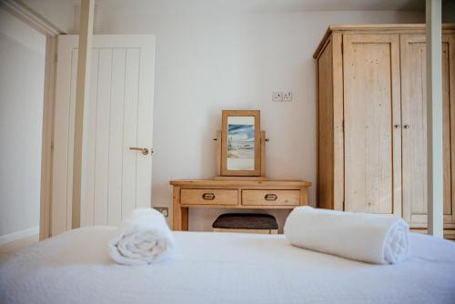 a bedroom with a bed with a dresser and a mirror at Sennen Cove Cottage in Sennen Cove