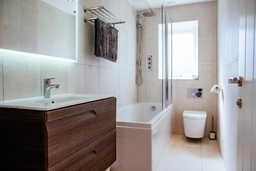 a bathroom with a sink and a tub and a toilet at Sennen Cove Cottage in Sennen Cove