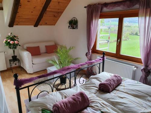1 dormitorio con cama, sofá y ventana en Gîte de la Motte en Tavannes