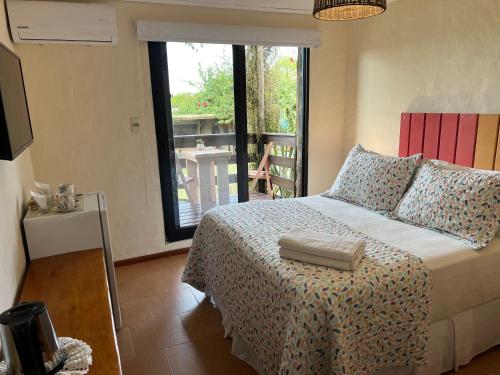 a bedroom with a large bed and a large window at Posada de la Viuda in Punta Del Diablo
