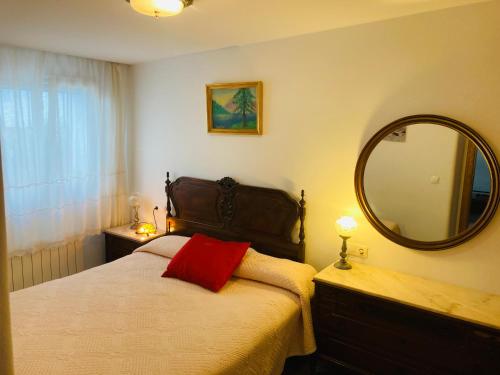een slaapkamer met een bed met een rood kussen en een spiegel bij Alojamiento rural Los Pérez Lucainena de las Torres in Lucainena de las Torres