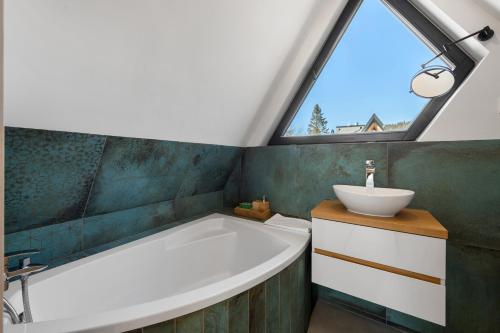 a bathroom with a tub and a sink and a window at Osada Gubałówka na Polanie Pająkówka & SPA in Kościelisko