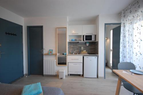 une cuisine avec des armoires blanches et une table dans une pièce dans l'établissement Saphir de Gruissan, à Gruissan