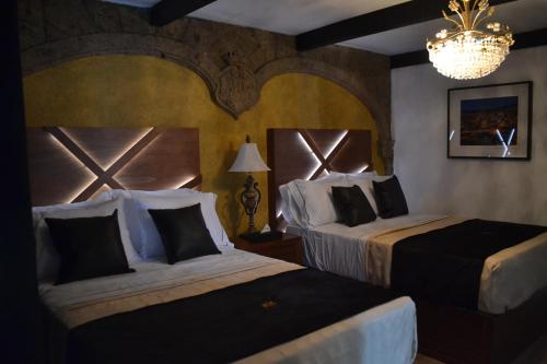 a hotel room with two beds and a chandelier at Hotel Boutique La Mansión Guadalajara in Guadalajara