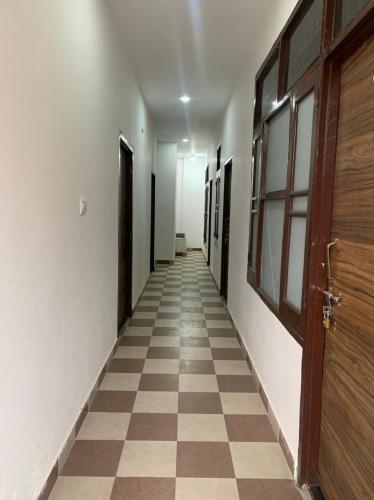 an empty hallway with a door and a checkered floor at Saatvik Homestay in Katra