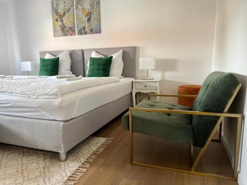 a bedroom with a bed and a green chair at ARGENTA Living 2 in Fulda