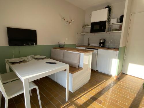 una pequeña cocina con mesa, mesa blanca y sillas en Studio La Pinède Plage à 150m Clim Place de Parking Privée, en Saint-Cyr-sur-Mer
