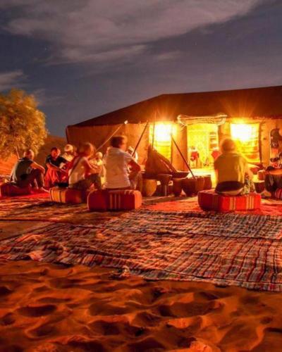 a group of people sitting in front of a tent at Overnight Desert Camp in Merzouga