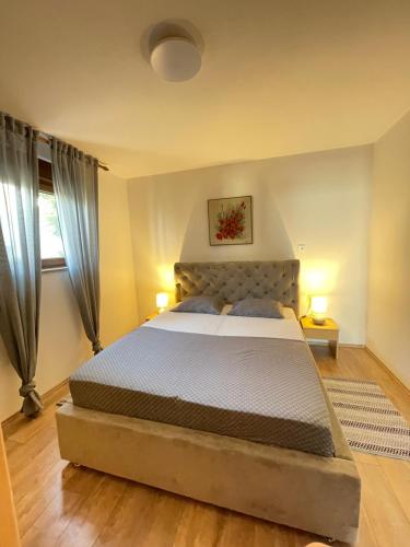 een slaapkamer met een groot bed met 2 lampen bij Apartmani Suzana in Klenovica