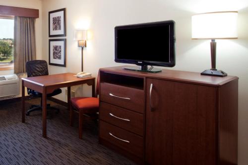 a hotel room with a television on a dresser with a desk at AmericInn by Wyndham Rexburg BYUI in Rexburg