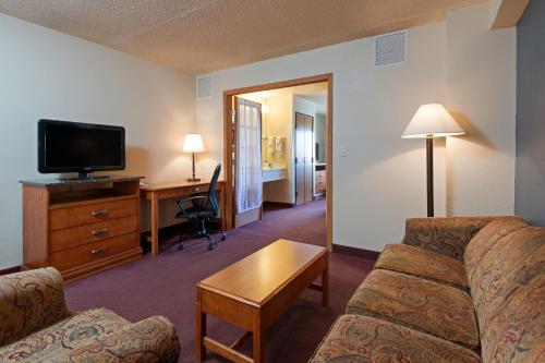 a living room with a couch and a desk and a television at AmericInn by Wyndham Rexburg BYUI in Rexburg