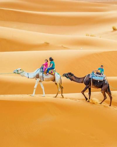 two people riding on camels in the desert at Overnight Desert Camp in Merzouga