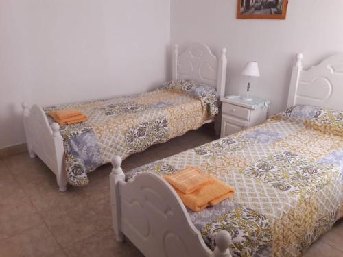 1 dormitorio con 2 camas y mesa con lámpara en Dptos Astrada en Goya