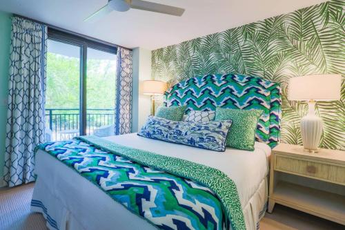 a bedroom with a bed with blue and green pillows at Array of Sunshine Condo in Isle of Palms