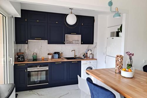 une cuisine avec des armoires bleu marine et une table en bois dans l'établissement HENRI CAMILLE REAL ESTATE -Beautiful one bedroom swimming pool and parking, à Cannes