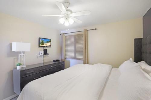 a bedroom with a white bed with a ceiling fan at Beachfront condo with restaurant, pool, spa and gym in Marco Island