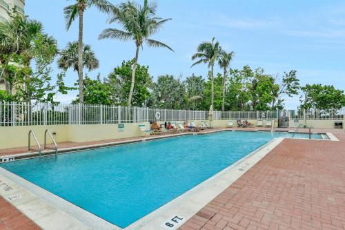 a swimming pool at a resort with palm trees at Beachfront condo with restaurant, pool, spa and gym in Marco Island
