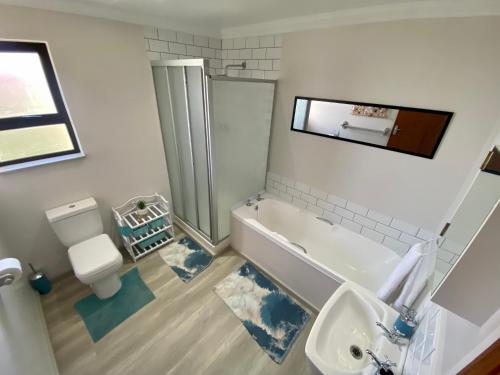 a bathroom with a tub and a toilet and a sink at Charlotte at Paradise Beach in Jeffreys Bay