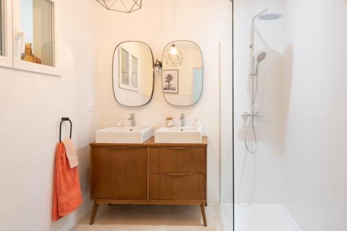 une salle de bain avec deux lavabos et deux miroirs dans l'établissement La Dolce Villa avec piscine chauffée & cigales, à Poulx