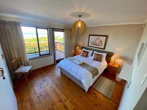 a bedroom with a bed and a large window at Charlotte at Paradise Beach in Jeffreys Bay