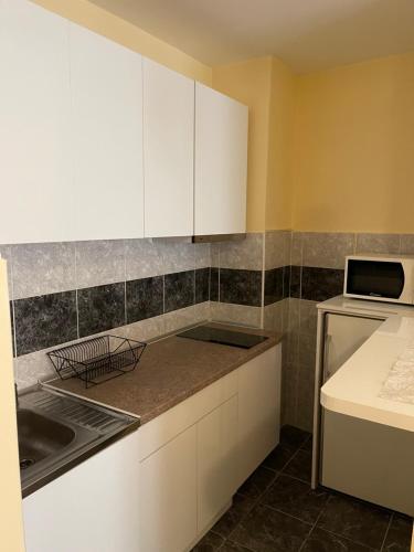 a kitchen with white cabinets and a sink and a microwave at Trident Apartments 2 in Niš
