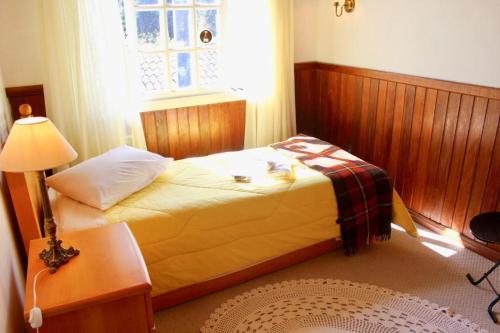 1 dormitorio con 1 cama con lámpara y ventana en Residencial Luíza, en Canela