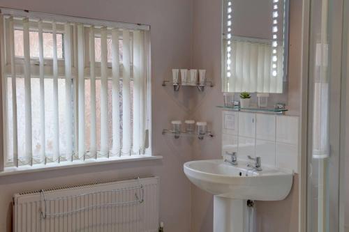 a bathroom with a sink and a mirror and a window at Best Western Deincourt Hotel in Newark upon Trent