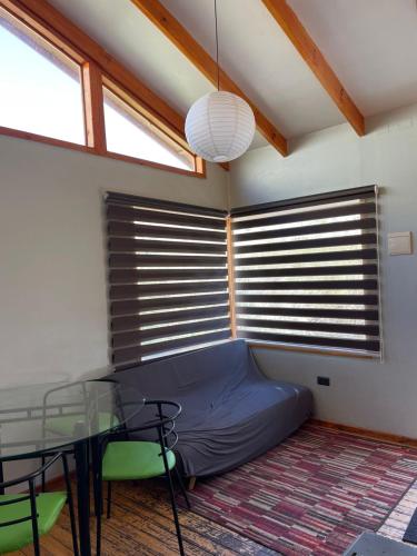 a room with a bed and a table and windows at Cabañas Luna de Cuarzo, Cochiguaz in Paihuano