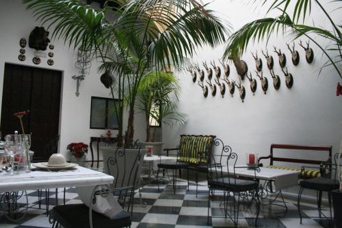 a dining room with tables and chairs and palm trees at Palacio San Bartolomé in El Puerto de Santa María