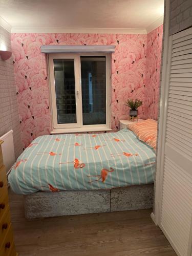 a bedroom with a bed with a pink wall at Poolside in Peacehaven