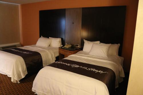a hotel room with two beds with white and brown sheets at Bradley Inn in Windsor Locks