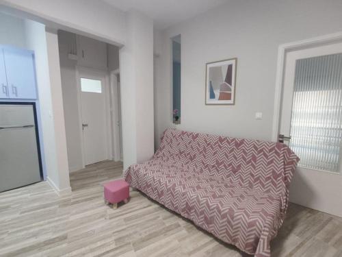 een woonkamer met een bed en een roze kruk bij Central Comfy Appartment in Agrinion