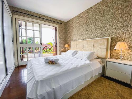 - une chambre avec un grand lit blanc et une fenêtre dans l'établissement LOCAR-IN GRAMADO - Apartamento Rua Torta, à Gramado