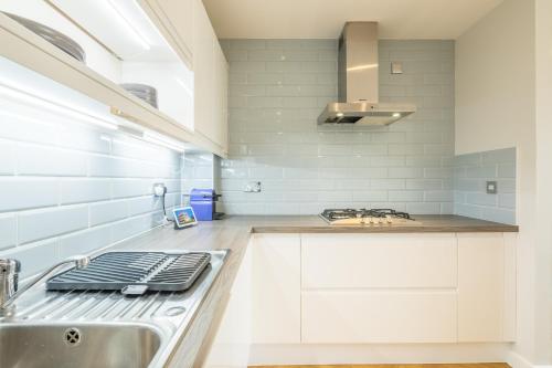 uma cozinha branca com um lavatório e um fogão em EXECUTIVE 2BR apartment next to Station + Parking em Cambridge