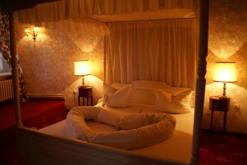 a bedroom with a canopy bed with two lamps at Hotel Burg Trendelburg in Trendelburg