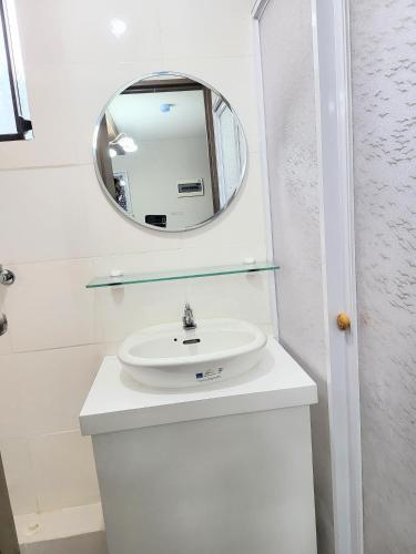 a white bathroom with a sink and a mirror at Kate's Corner @ One oasis Condo in Cagayan de Oro