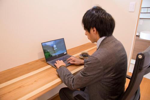 a man sitting at a desk using a laptop computer at Ryokan Seifuso in Ōmuta