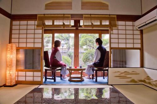 two women sitting in chairs looking out of a window at Ryokan Seifuso in Ōmuta
