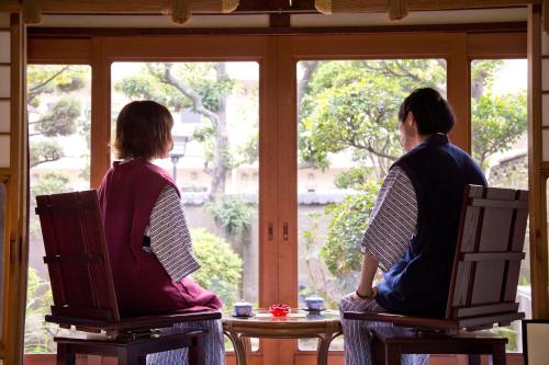 a man and woman sitting in chairs looking out of a window at Ryokan Seifuso in Ōmuta