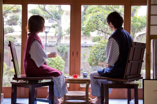 two people sitting on chairs looking out of a window at Ryokan Seifuso in Ōmuta