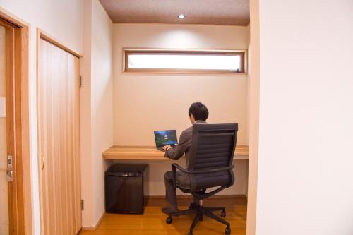 a man sitting at a desk with a laptop at Ryokan Seifuso in Ōmuta
