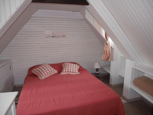 1 cama roja con 2 almohadas en el ático en Breton granite stone house, Camaret-sur-Mer, en Camaret-sur-Mer
