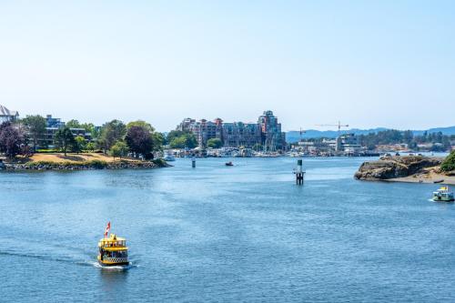 a yellow boat on a river with buildings in the background at Victoria Regent Waterfront Hotel & Suites in Victoria