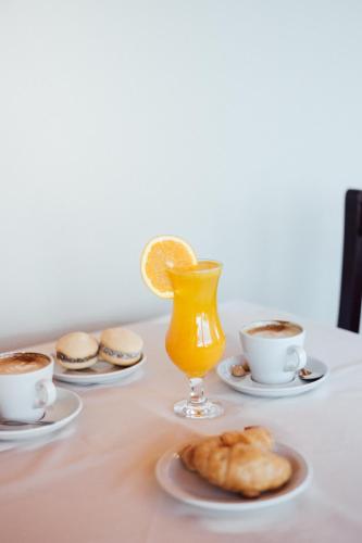 a table with cups of coffee and a glass of orange juice at Hotel Ikera in Hernando