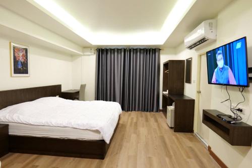 a hotel room with a bed and a flat screen tv at Young Coconut Garden Home Resort in Amphawa