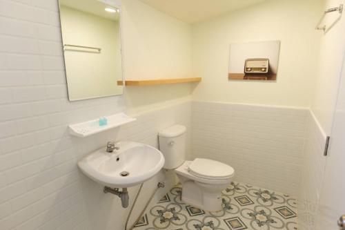 La salle de bains est pourvue de toilettes, d'un lavabo et d'un miroir. dans l'établissement Young Coconut Garden Home Resort, à Amphawa
