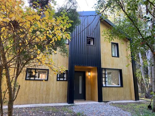 una casa con fachada negra y ventanas en Casa del Bosque en San Carlos de Bariloche