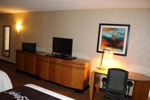 a hotel room with a bed and a desk with a television at Bradley Inn in Windsor Locks